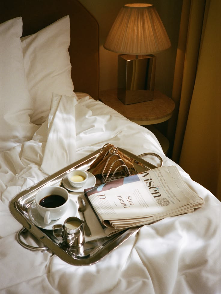 Breakfast tray served on a hotel bed in warm morning light